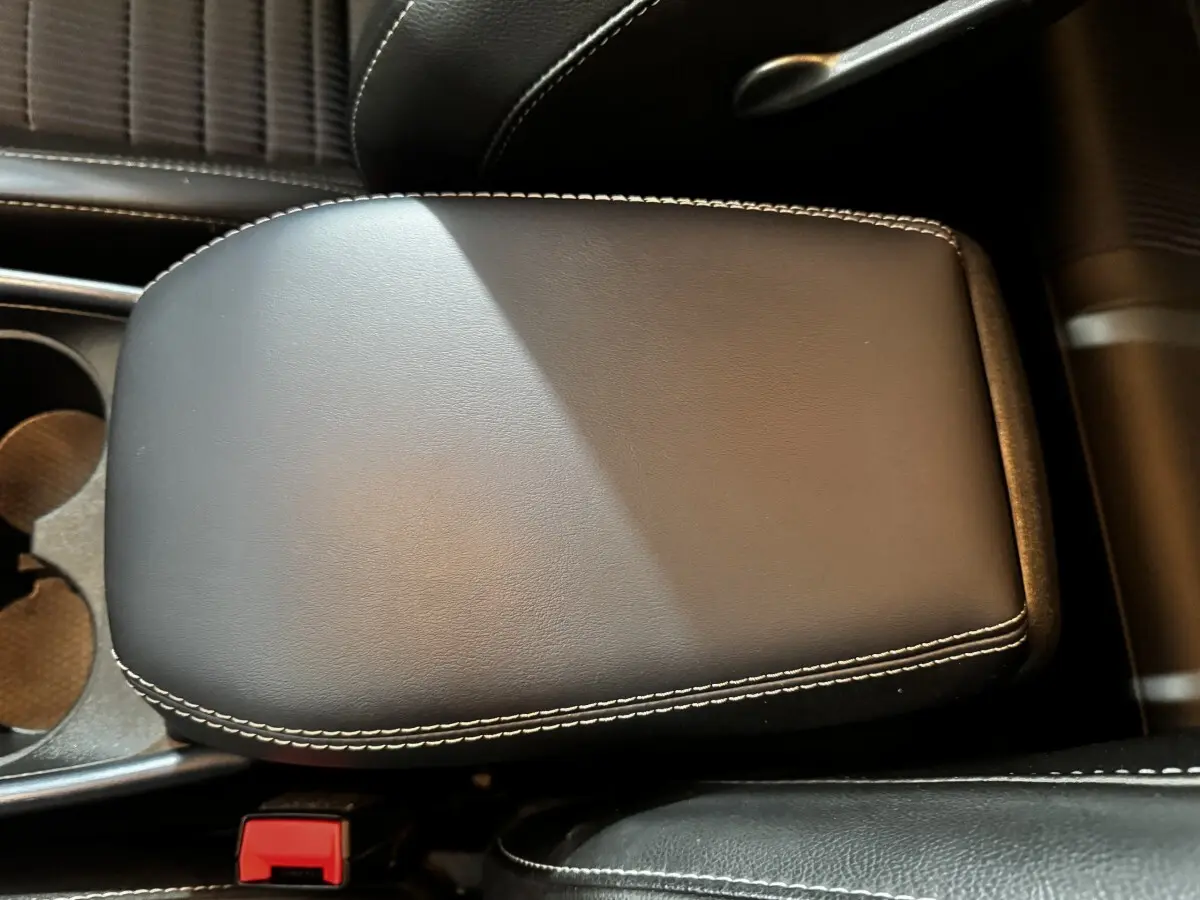 Gros plan sur l'accoudoir central en cuir noir avec surpiqûres blanches du Nissan Qashqai e-Power 190 Tekna BVA 2023.