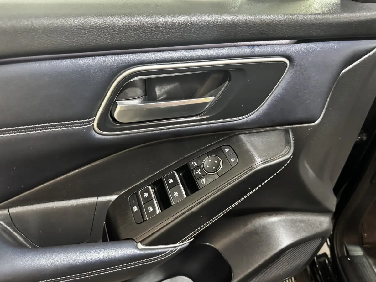 Détail de la porte intérieure côté conducteur du Nissan Qashqai e-Power 190 Tekna 2023 en cuir noir avec commandes électriques.