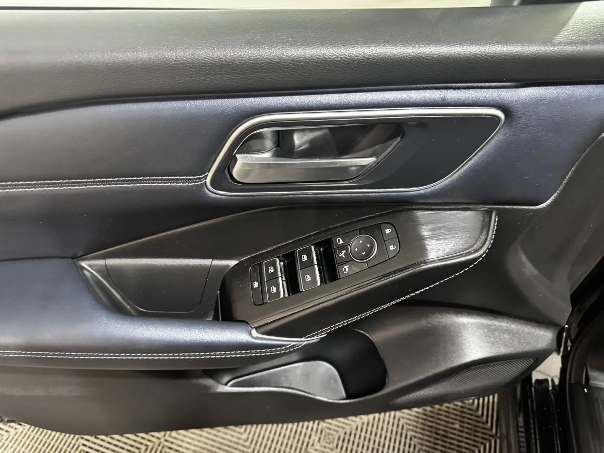 Détail de la porte avant gauche noire du Nissan Qashqai e-Power 190 Tekna avec commandes des vitres et rétroviseurs.
