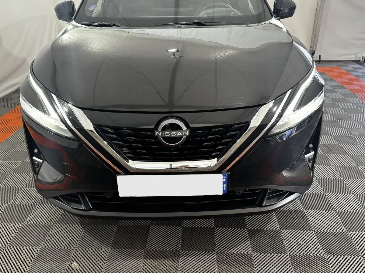 Vue frontale d'un Nissan Qashqai e-Power 190 Tekna BVA noir avec calandre chromée et phares LED allumés.