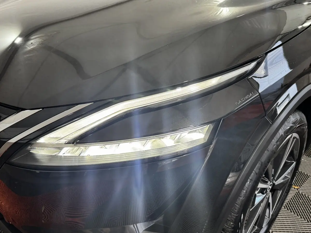 Gros plan sur le phare avant droit du Nissan Qashqai e-Power noir, soulignant le design LED et la jante alliage visible.