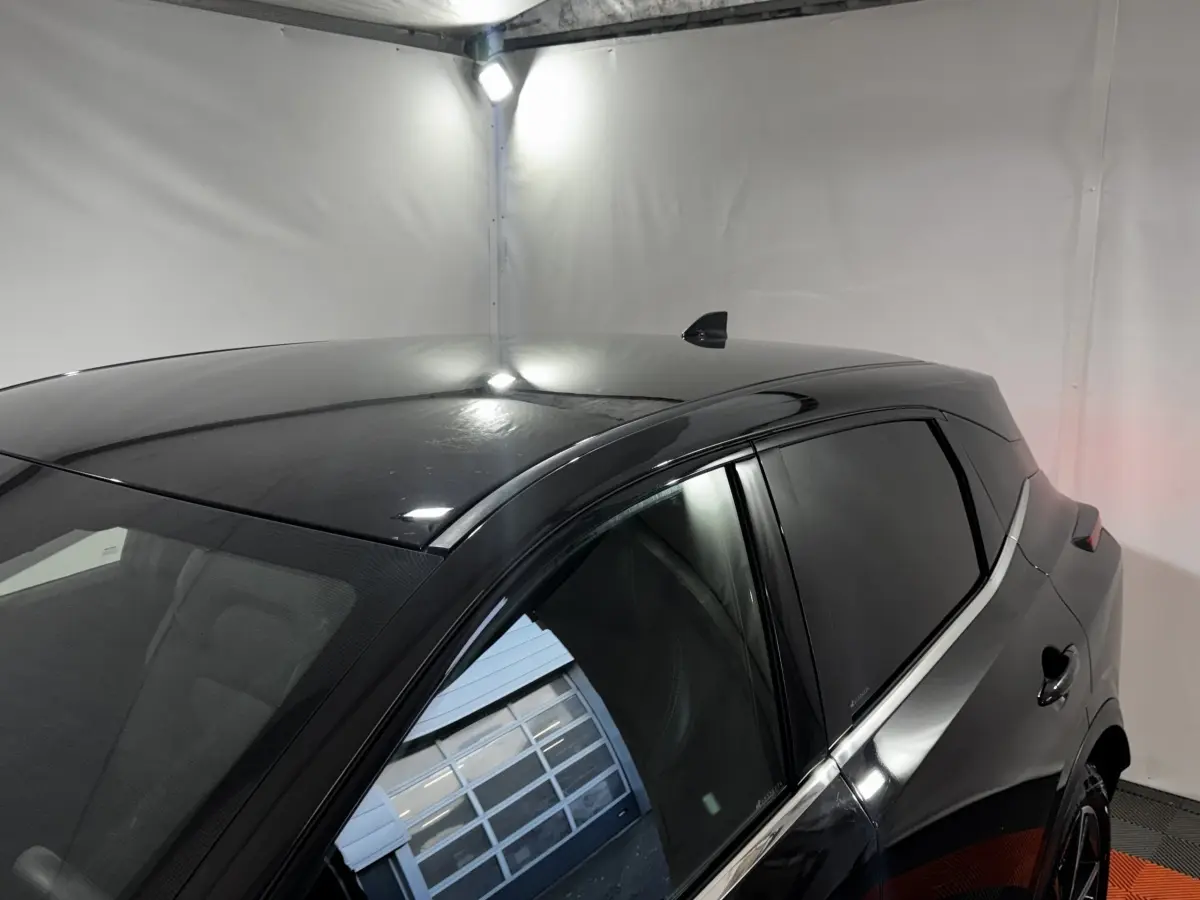 Vue 3/4 arrière droite du Nissan Qashqai e-Power 190 Tekna noir avec vitres teintées dans un garage blanc.