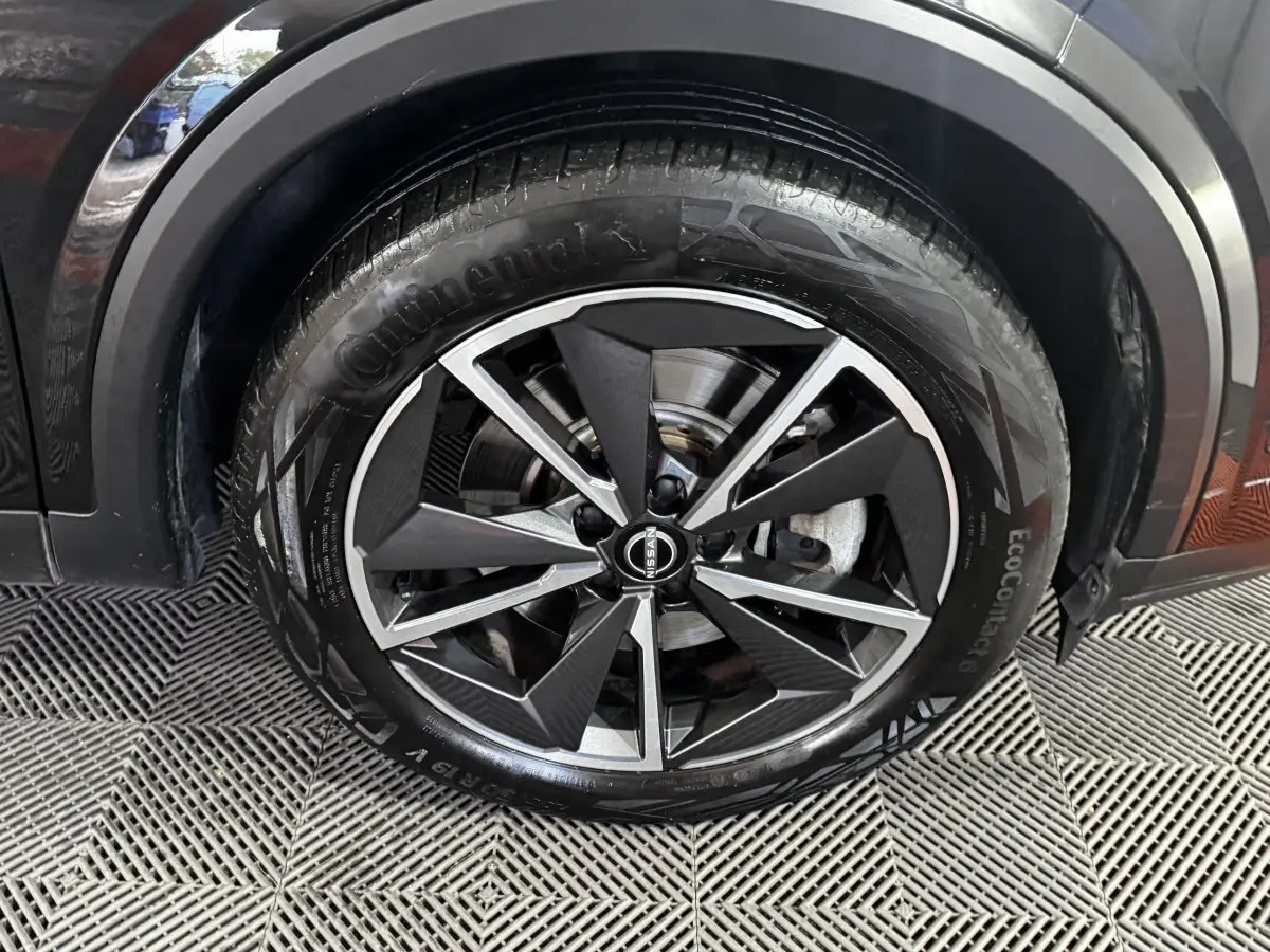 Gros plan sur la roue avant droite noire du Nissan Qashqai e-Power 190 Tekna BVA avec jante alliage bicolore.