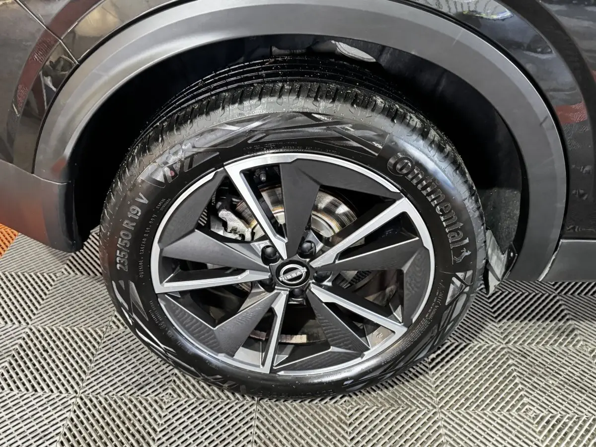 Gros plan sur la roue avant droite noire du Nissan Qashqai e-Power 190 Tekna BVA avec jante alliage bicolore.
