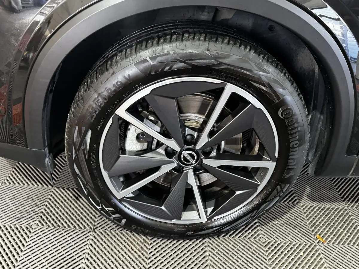 Gros plan sur la roue avant droite noire du Nissan Qashqai e-Power 190 Tekna BVA avec jante alliage distinctive.