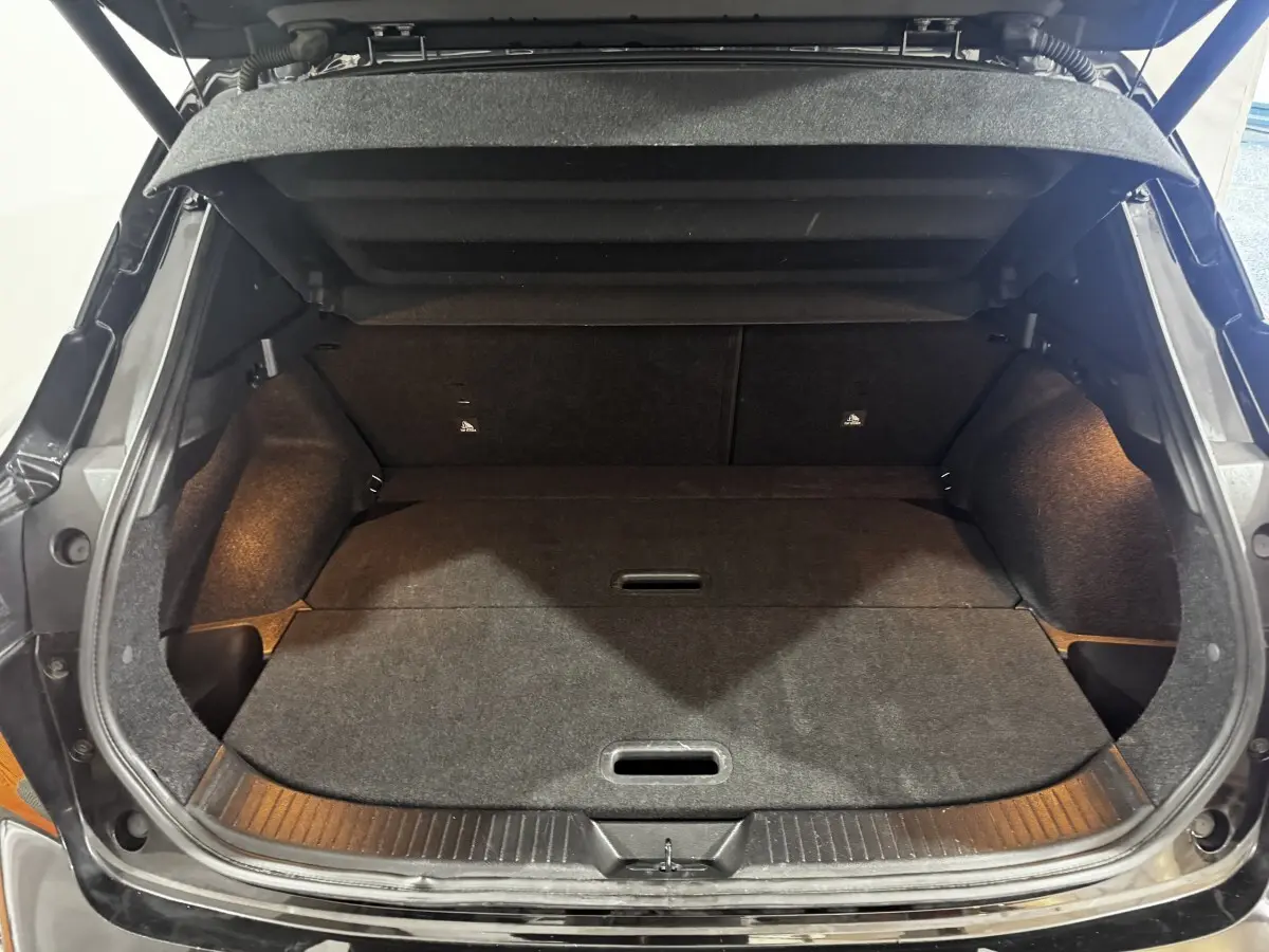 Coffre ouvert noir du Nissan Qashqai e-Power 190 Tekna 2023, vue intérieure montrant l'espace de chargement plat et éclairé.