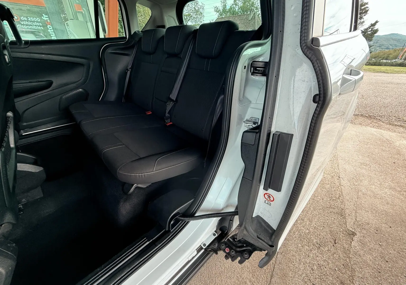 Vue intérieure arrière côté droit d'un Ford B-MAX blanc, montrant la banquette arrière en tissu gris noir.