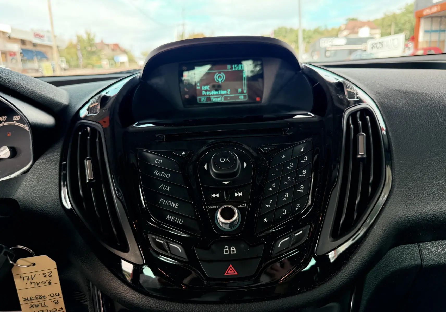 Vue rapprochée du tableau de bord noir brillant avec commandes multimédia d'une Ford B-MAX blanche de 2014.