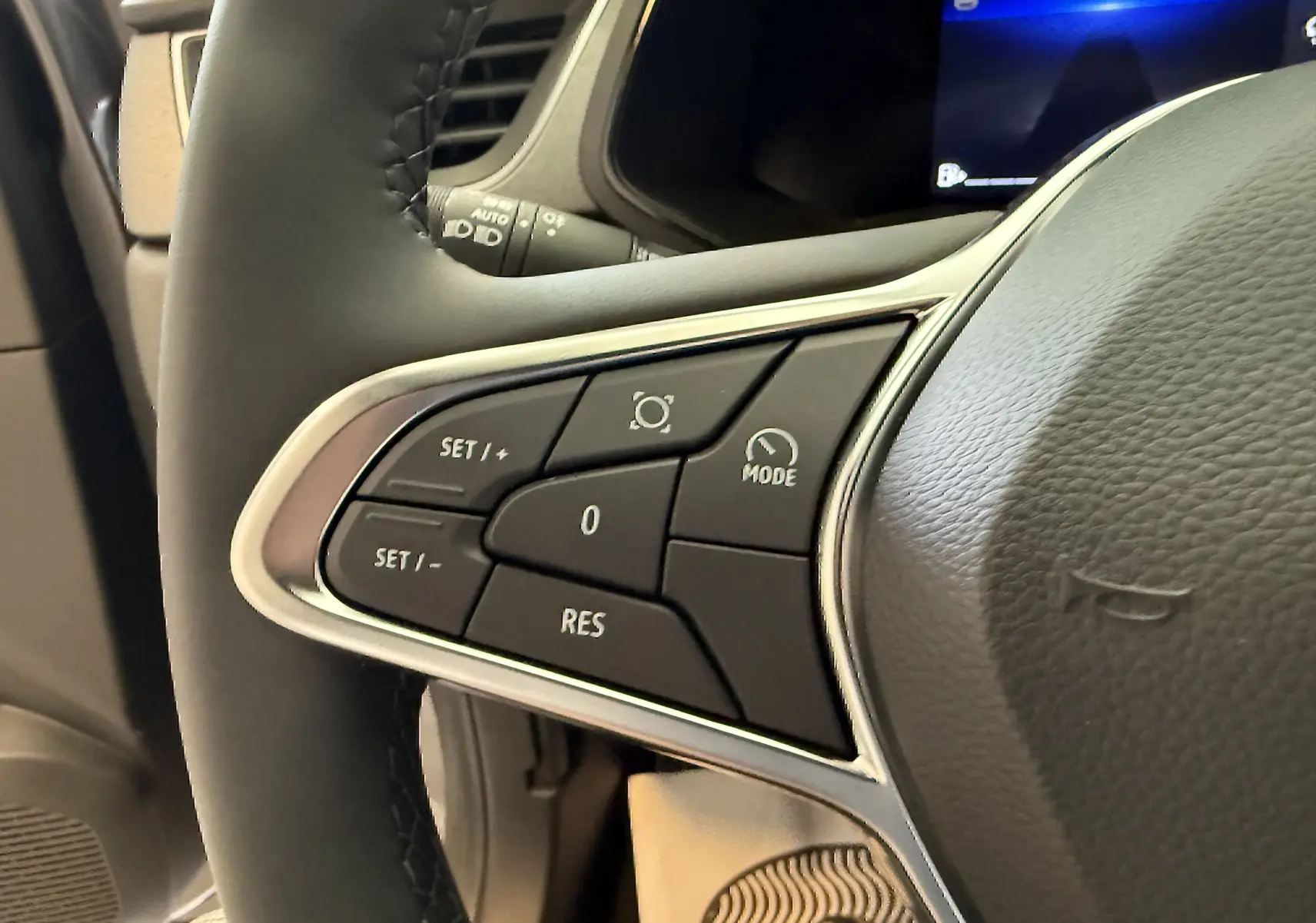 Gros plan sur les commandes au volant à gauche du Renault Captur gris Cassiopée, soulignant les boutons de régulateur de vitesse.
