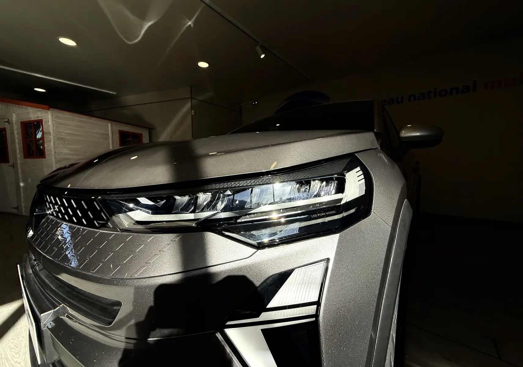 Gros plan sur l'avant droit du Renault Captur gris Cassiopée métal, mettant en valeur le phare LED et la calandre distinctive.