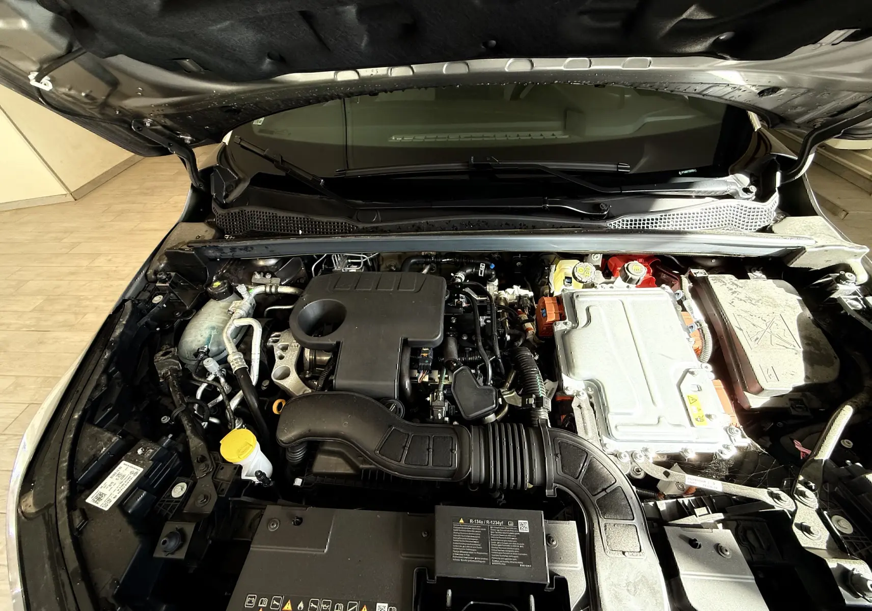 Vue rapprochée du moteur hybride du Renault Captur 2025, capot ouvert, montrant les composants mécaniques et électriques.