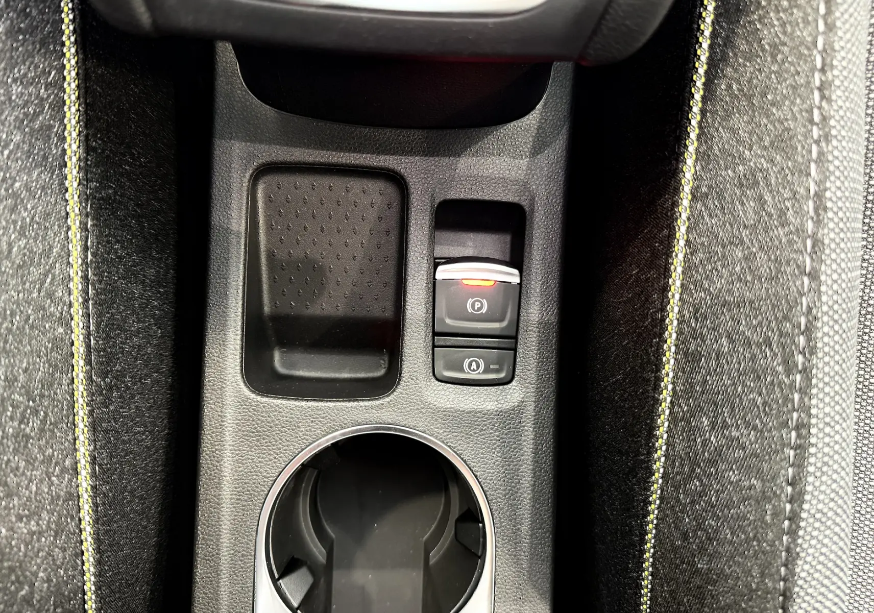 Gros plan sur la console centrale du Renault Captur 2025, montrant le porte-gobelet et les boutons de frein à main électrique et start/stop.