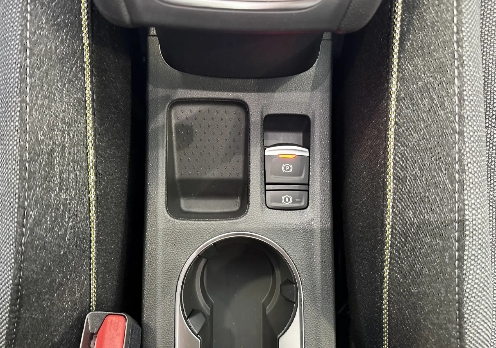 Vue plongeante sur la console centrale du Renault Captur gris cassiopée, avec porte-gobelet et boutons de frein à main électrique.