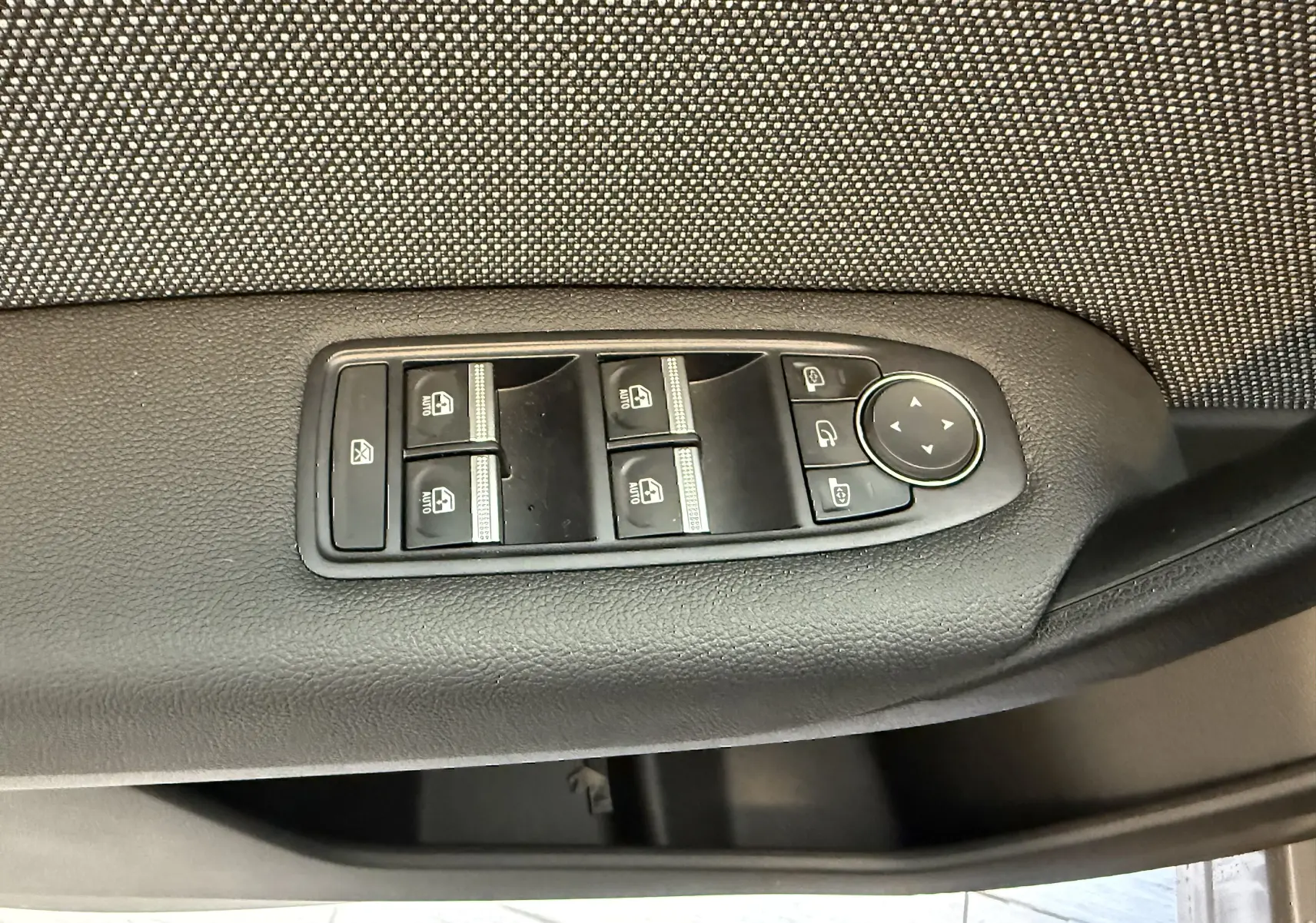 Gros plan sur les commandes de lève-vitres et rétroviseurs côté gauche de la porte d’un Renault Captur gris cassiopée 2025.