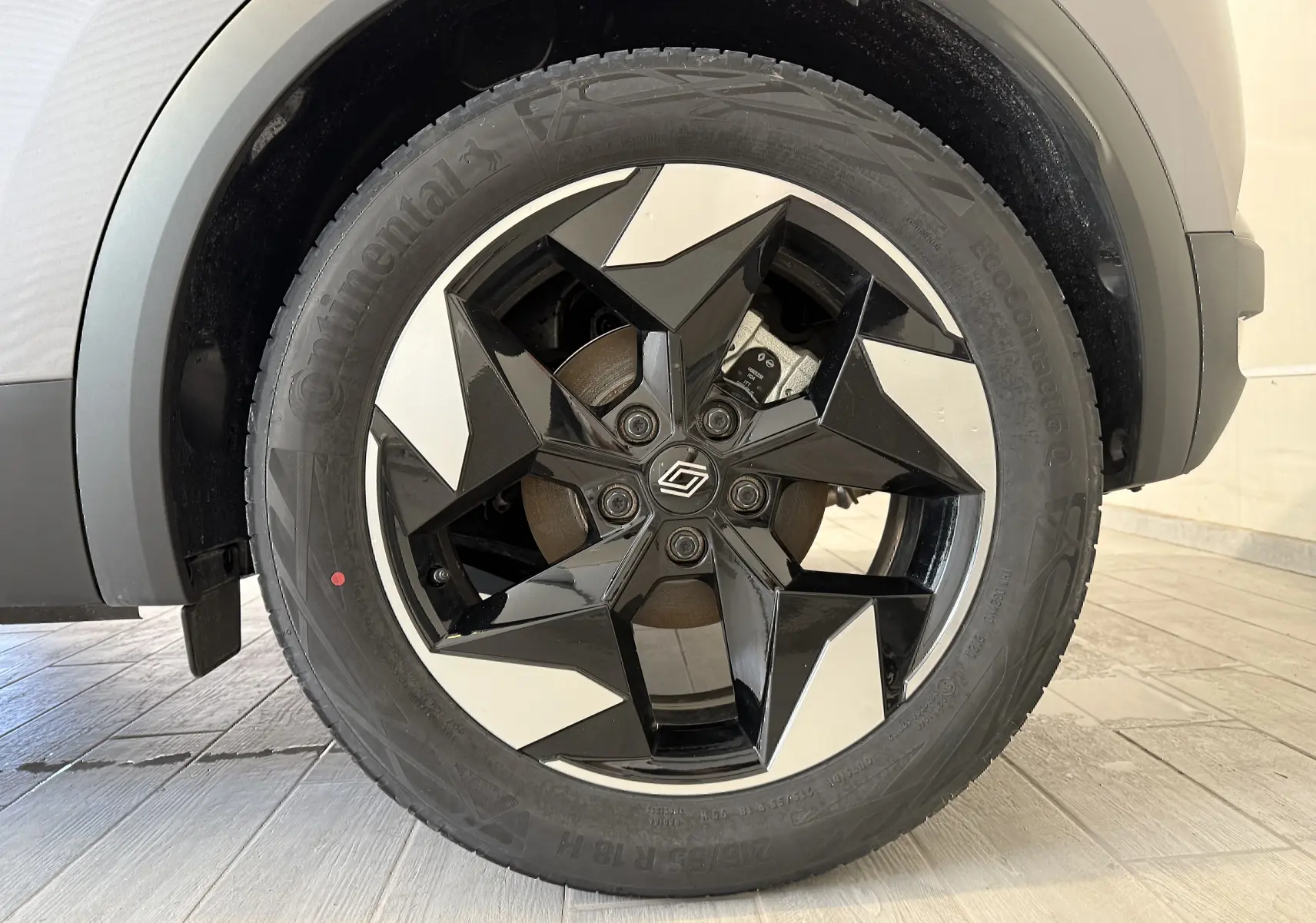 Gros plan sur la roue avant droite du Renault Captur gris Cassiopée Métal, jante alliage noire et argentée au design géométrique.