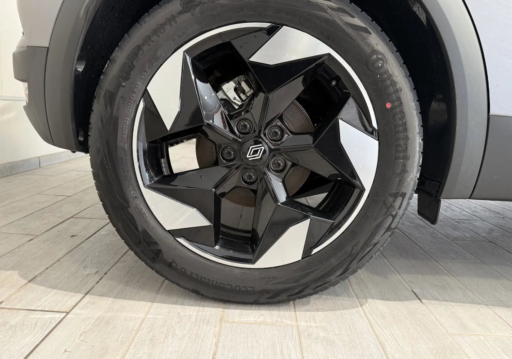 Gros plan sur la roue avant droite du Renault Captur gris Cassiopée, mettant en valeur la jante noire et argentée au design géométrique.