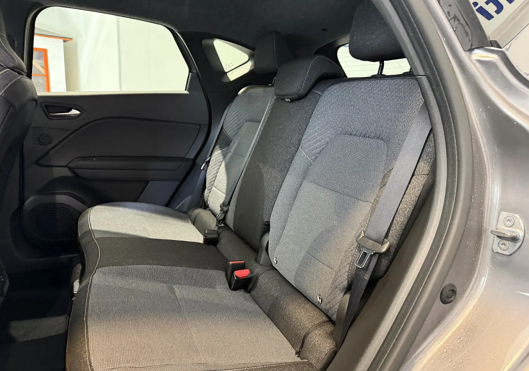 Vue intérieure côté droit des sièges arrière gris d'un Renault Captur 2025 hybride avec portière ouverte.