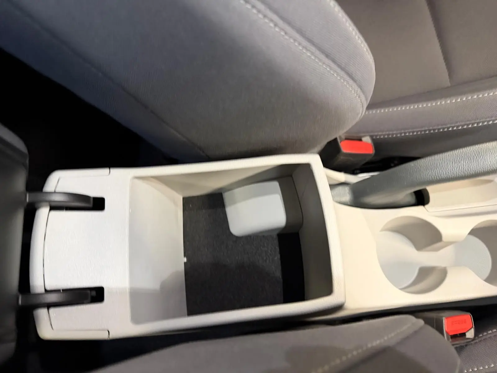 Vue plongeante sur la console centrale beige ouverte du Hyundai Bayon 2025 avec porte-gobelets et sièges gris.