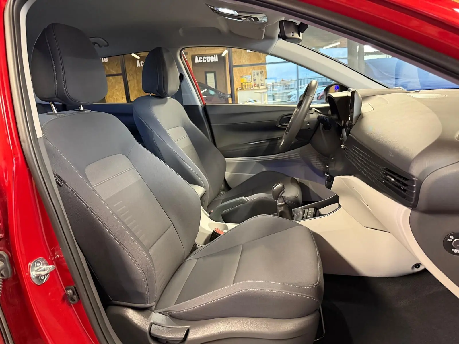 Intérieur avant du Hyundai Bayon rouge 2025, sièges tissu noir, tableau de bord bicolore noir et gris clair.