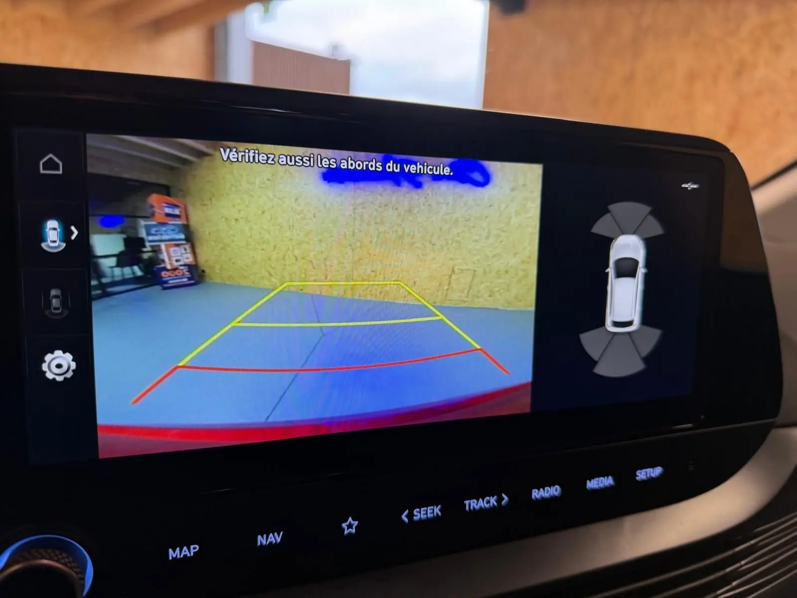 Écran tactile intérieur montrant la caméra de recul et l'aide au stationnement du Hyundai Bayon rouge 2025.