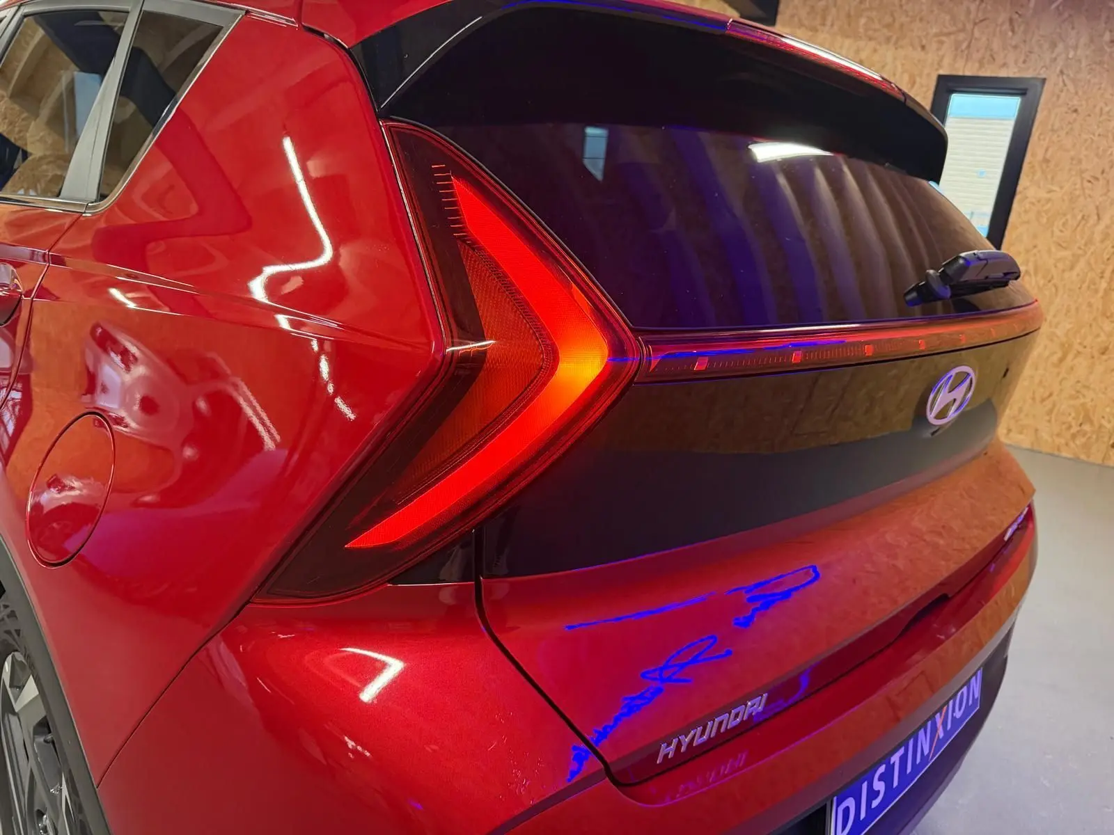 Feu arrière en forme de flèche rouge sur l'arrière droit d'une Hyundai Bayon rouge avec hayon noir laqué.