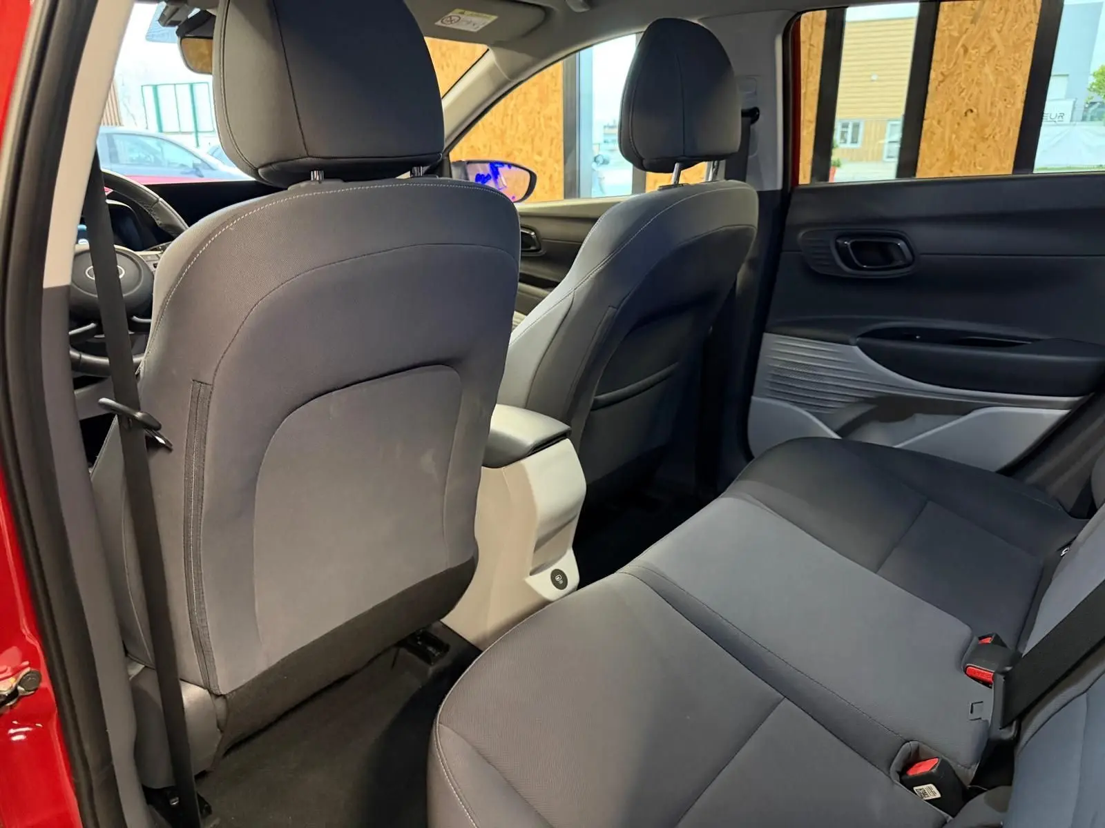 Vue intérieure arrière du Hyundai Bayon rouge 2025, sièges tissu bi-ton noir et gris clair avec accoudoir central.