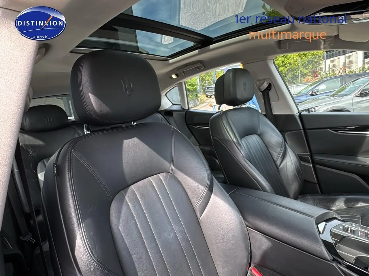 Vue intérieure montrant les sièges avant en cuir noir avec logo Maserati, toit ouvrant panoramique et console centrale.