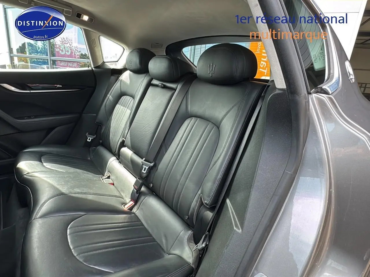 Vue intérieure côté droit montrant la banquette arrière en cuir noir du Maserati Levante gris 2017 avec appuis-tête trident brodés.