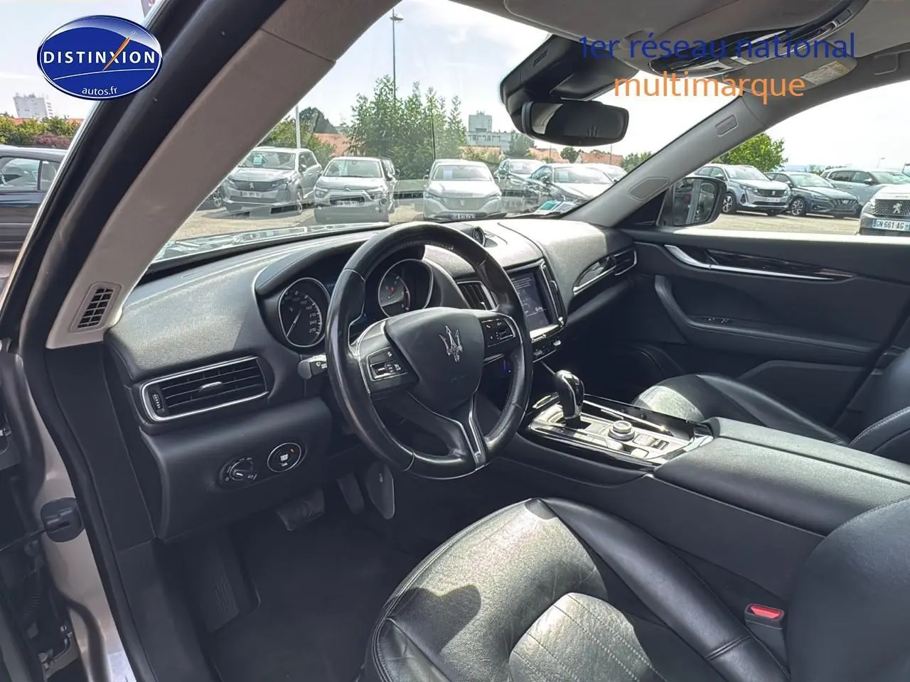 Intérieur côté conducteur du Maserati Levante gris 2017, avec volant cuir et console centrale moderne.