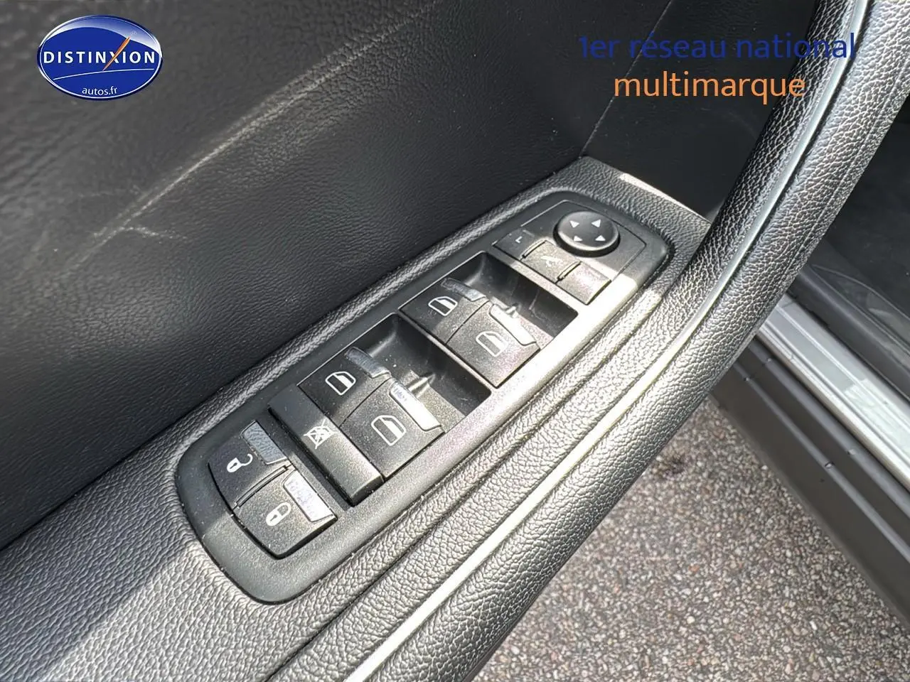 Gros plan sur les commandes des vitres électriques et rétroviseurs sur la porte côté conducteur d'une Maserati Levante gris.