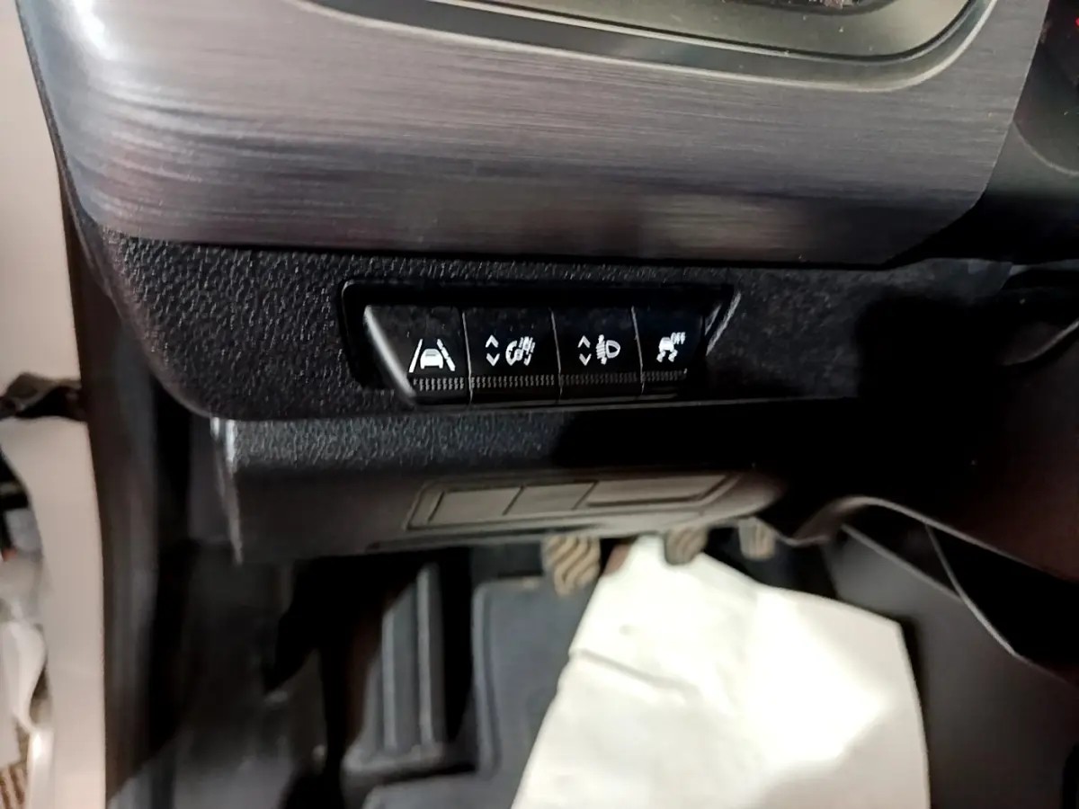 Vue intérieure du tableau de bord côté gauche du Renault Kangoo blanc, avec boutons de contrôle d’aides à la conduite.