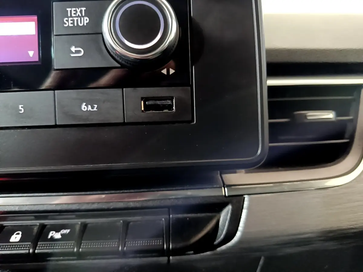 Gros plan sur la console centrale noire du Renault Kangoo blanc 2022, avec bouton de réglage et port USB visible.