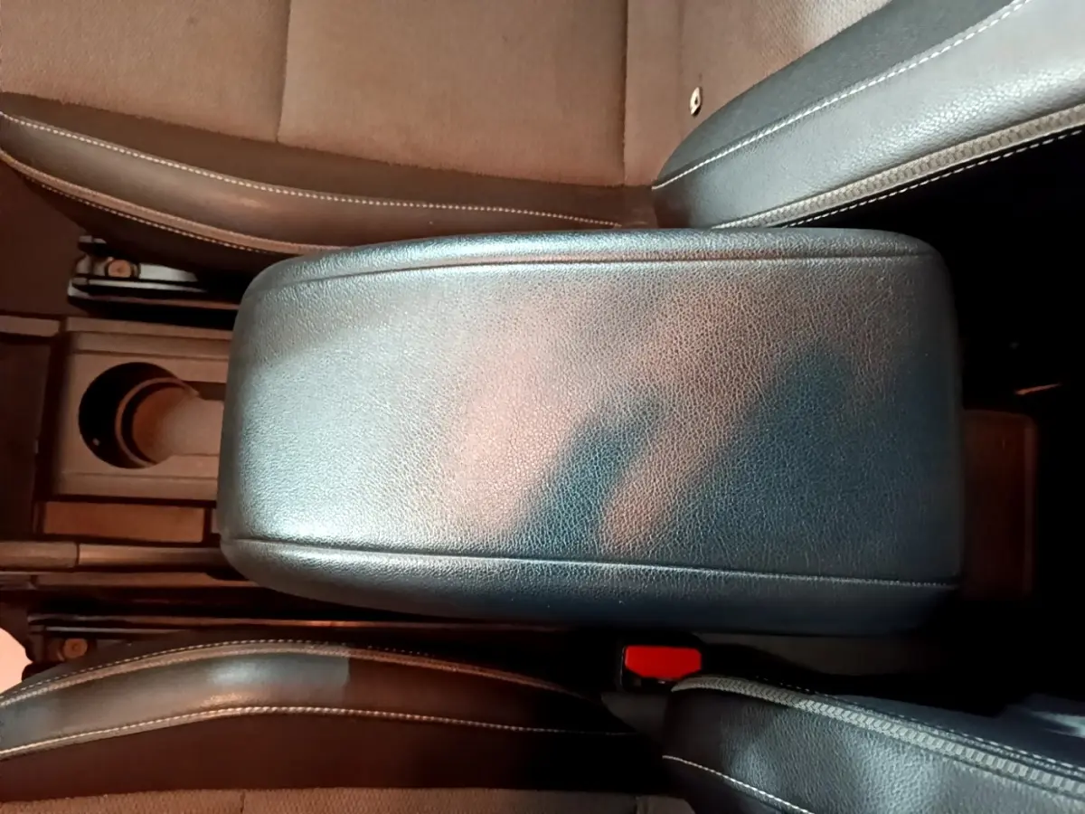 Gros plan sur l'accoudoir central noir entre les sièges avant du Renault Kangoo blanc, version Équilibre 2022.