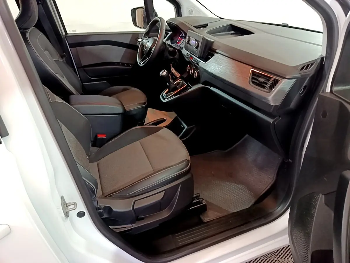 Vue intérieure côté conducteur du Renault Kangoo blanc 2022, montrant sièges tissu et tableau de bord avec écran tactile central.