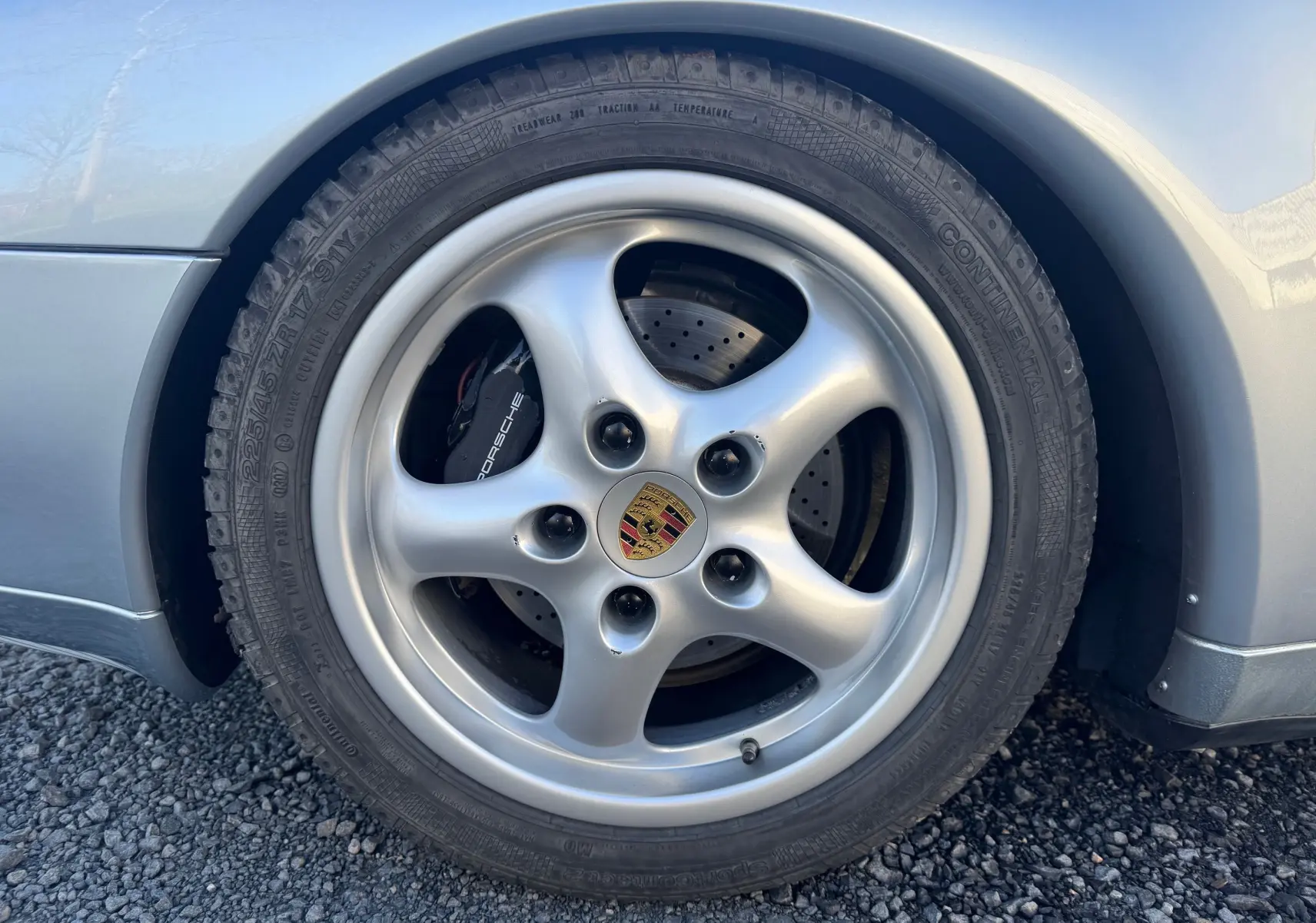 Gros plan sur la roue avant droite grise d'une Porsche 911 Carrera 2 type 993 avec jante alliage 17 pouces.