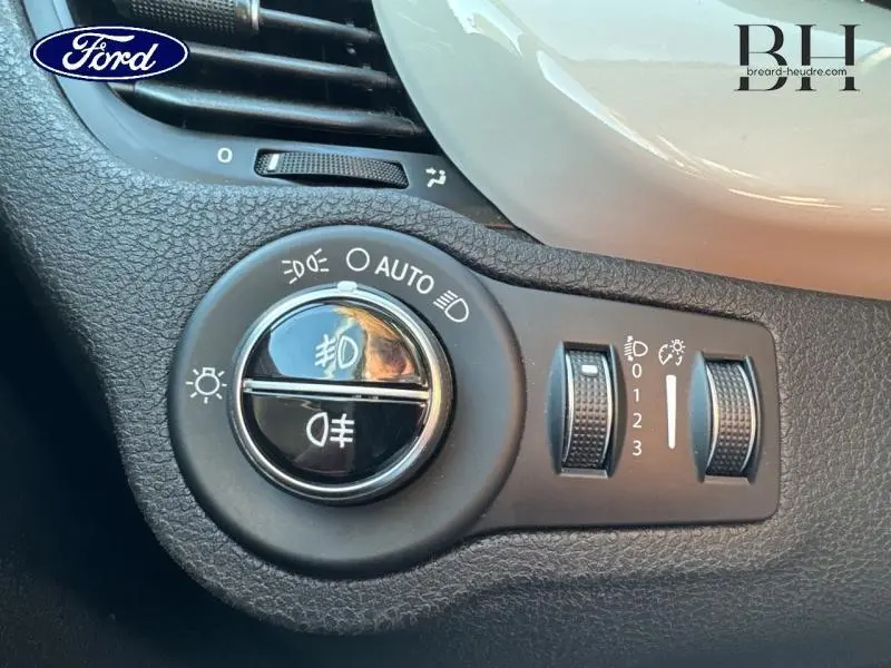 Gros plan sur les commandes d'éclairage d'une FIAT 500X argentée, avec réglages de phares et ventilation partielle visible.