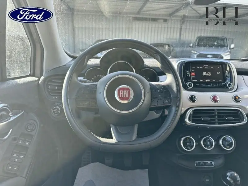 Vue intérieure frontale du tableau de bord et volant cuir noir avec logo FIAT rouge au centre, écran tactile et commandes intégrées.