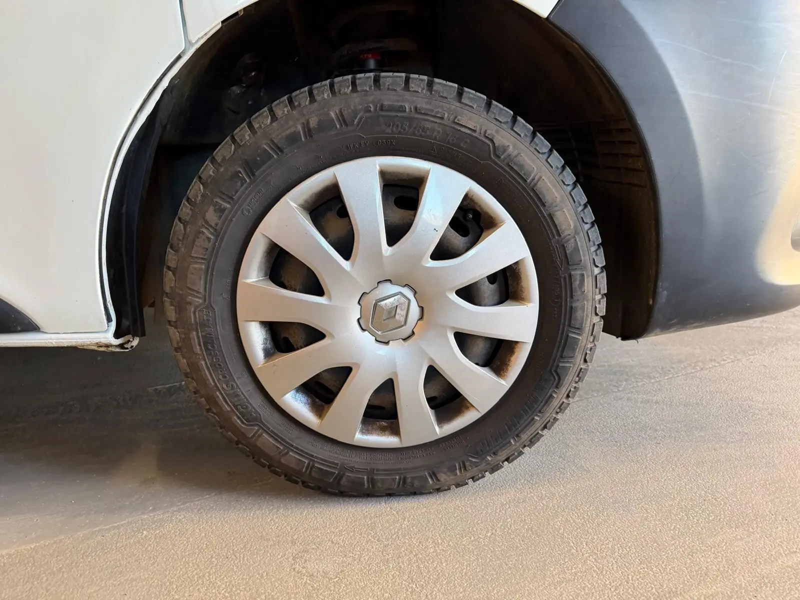 Gros plan sur la roue avant droite blanche d’un Renault Trafic Fourgon 2017 avec jante en plastique gris clair.