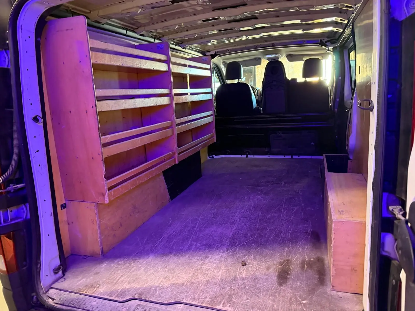 Vue intérieure arrière du Renault Trafic blanc 2017 avec aménagements en bois sur le côté gauche et droite.