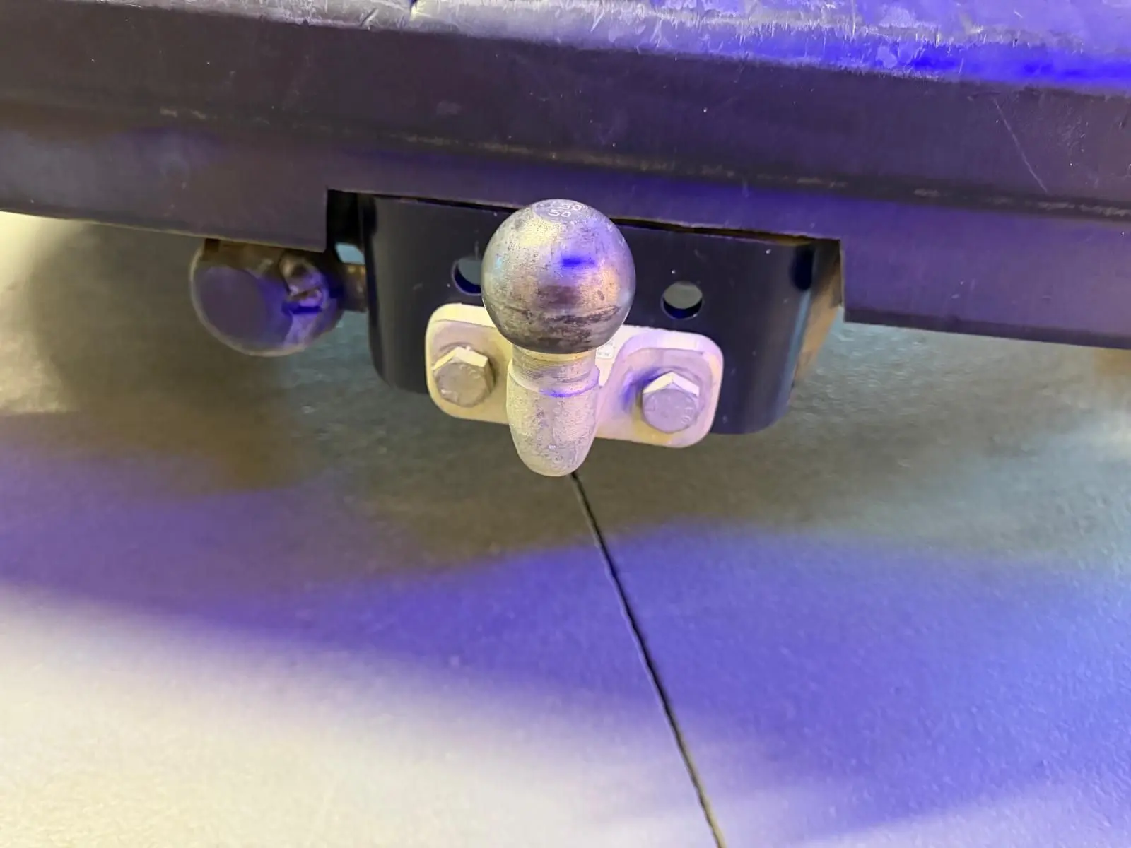 Gros plan sur l'attelage arrière métallique du Renault Trafic Fourgon blanc, sous le pare-chocs.