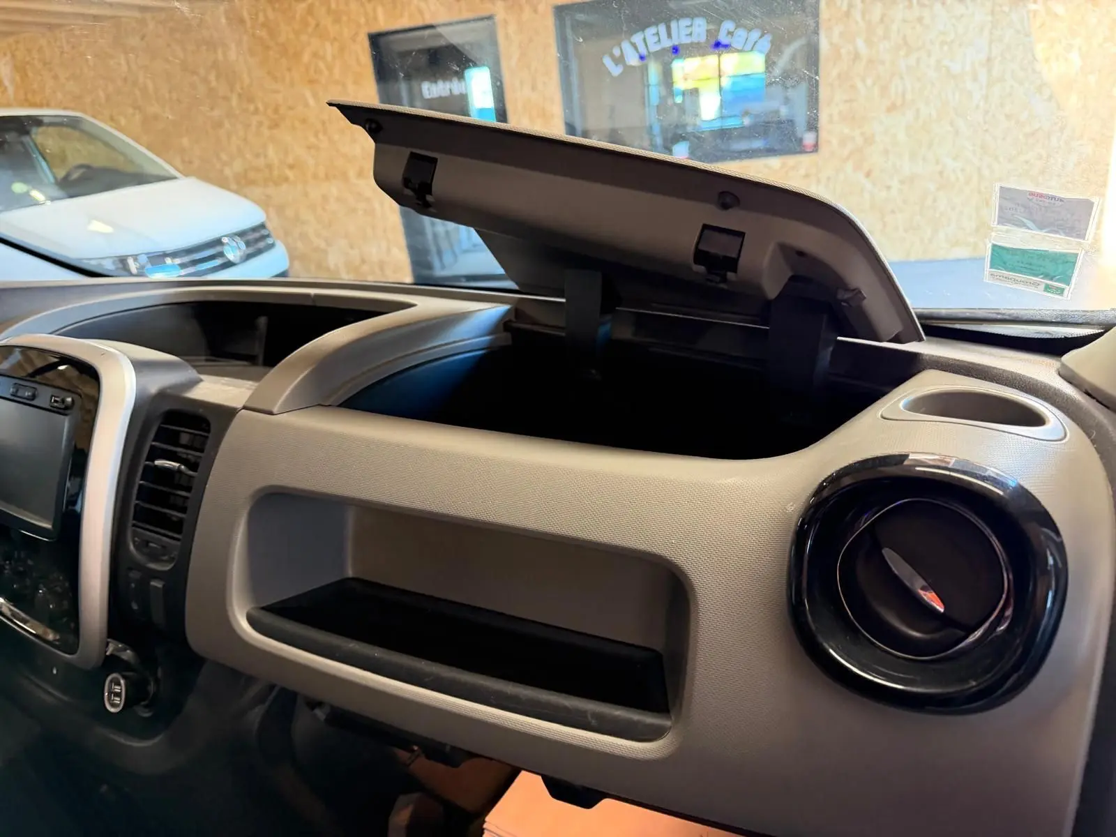 Vue intérieure du tableau de bord du Renault Trafic Fourgon blanc 2017, avec boîte à gants ouverte et habillage bois visible.