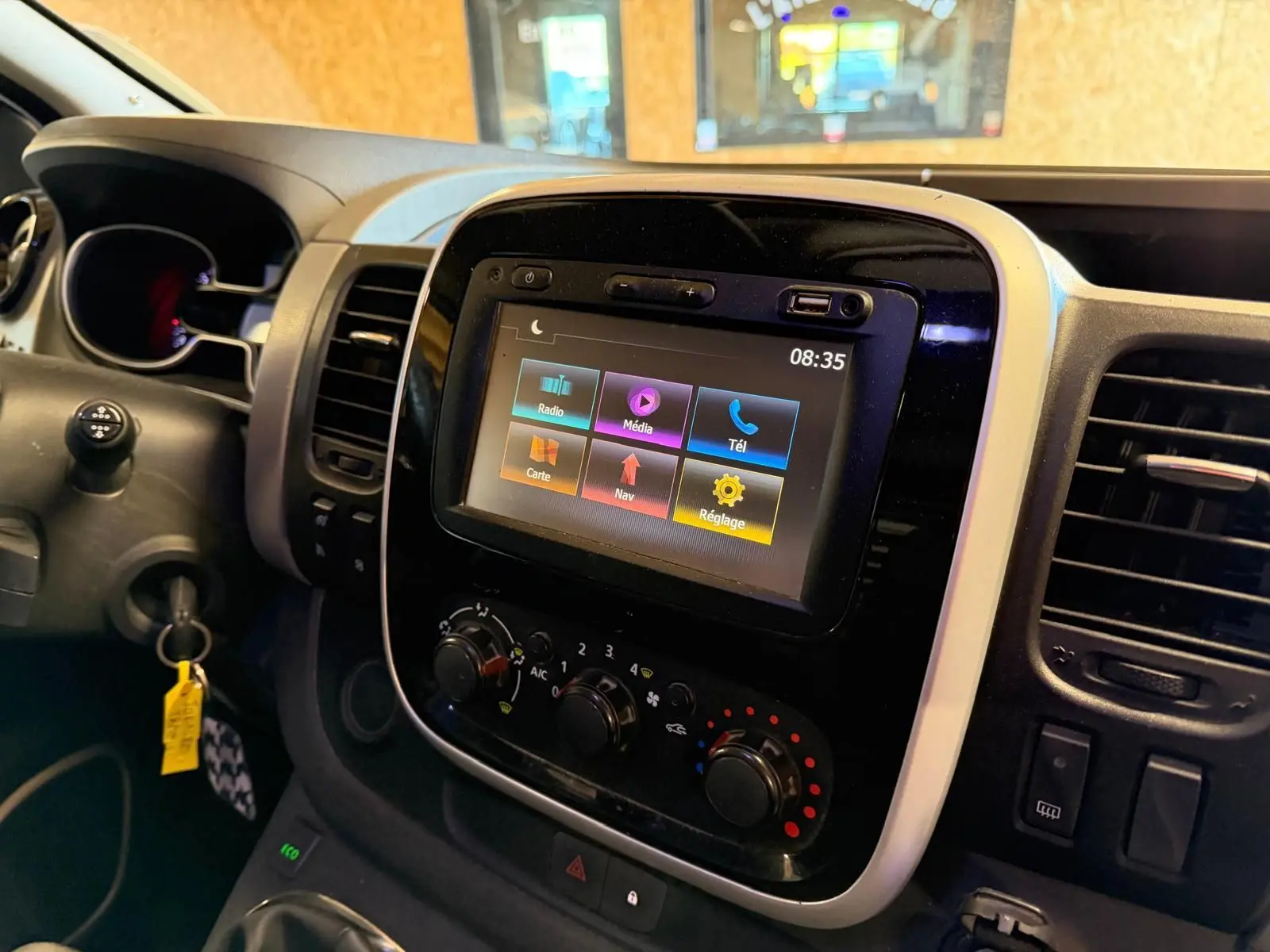 Vue rapprochée du tableau de bord du Renault Trafic Fourgon blanc, avec écran tactile et commandes de climatisation.