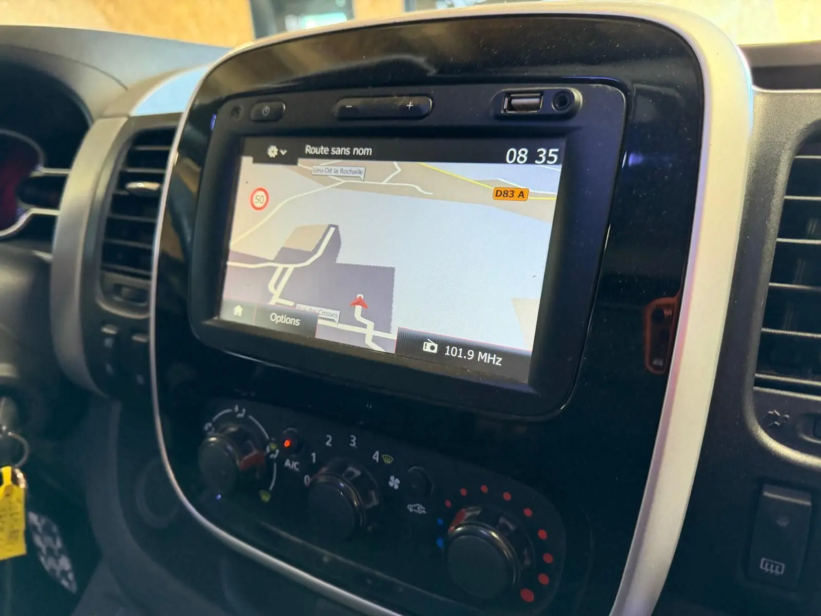 Gros plan sur le tableau de bord du Renault Trafic Fourgon 2017 avec écran GPS et commandes de climatisation.