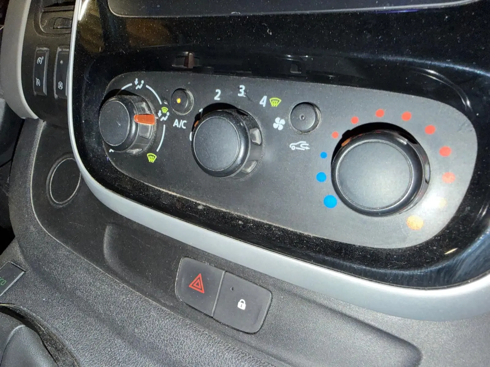 Gros plan sur les commandes de climatisation et ventilation du Renault Trafic Fourgon blanc, avec boutons rotatifs noirs.