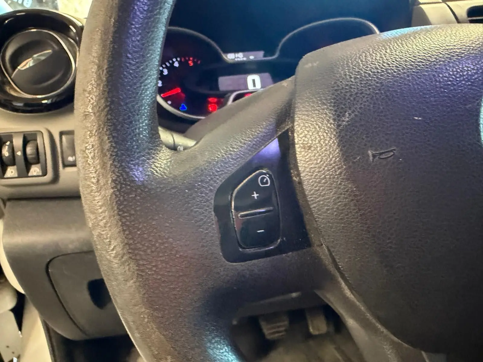 Gros plan sur le volant noir du Renault Trafic Fourgon blanc, avec tableau de bord et commandes visibles en arrière-plan.