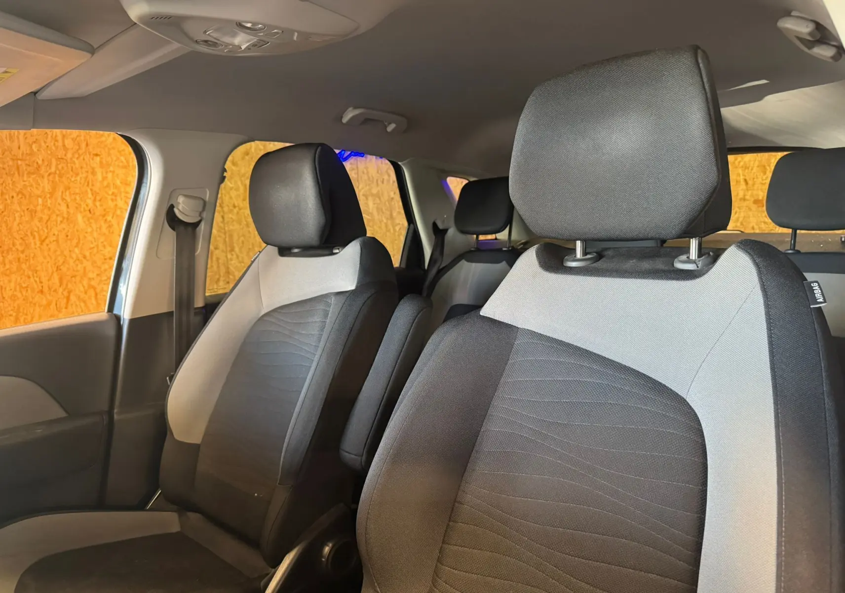 Vue intérieure sur les sièges avant gris et noirs du Citroën C4 Picasso 2016, avec appuie-têtes et ceintures visibles.