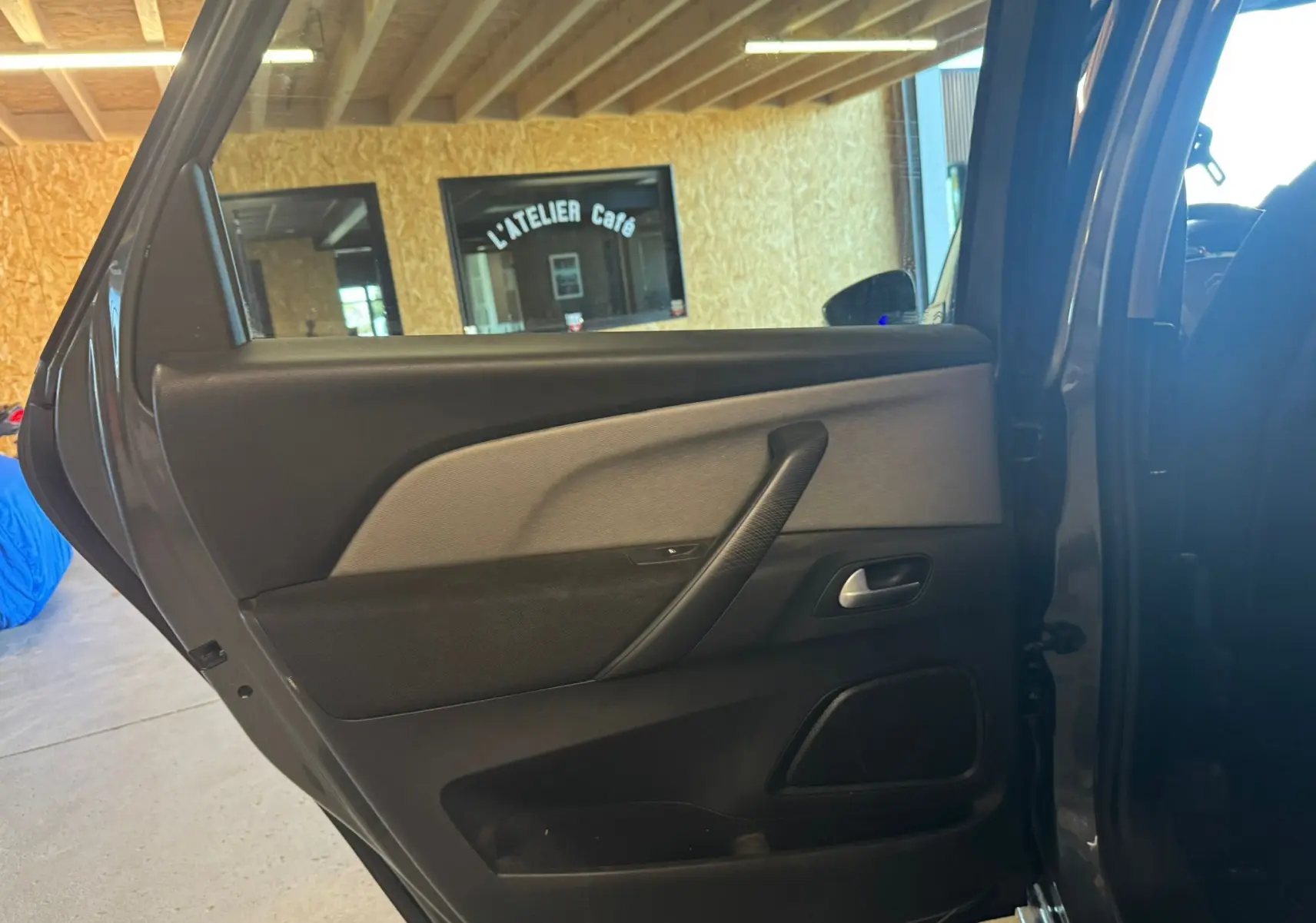 Vue intérieure côté gauche de la porte arrière grise d'une Citroën C4 Picasso 2016 avec garniture noire et beige.