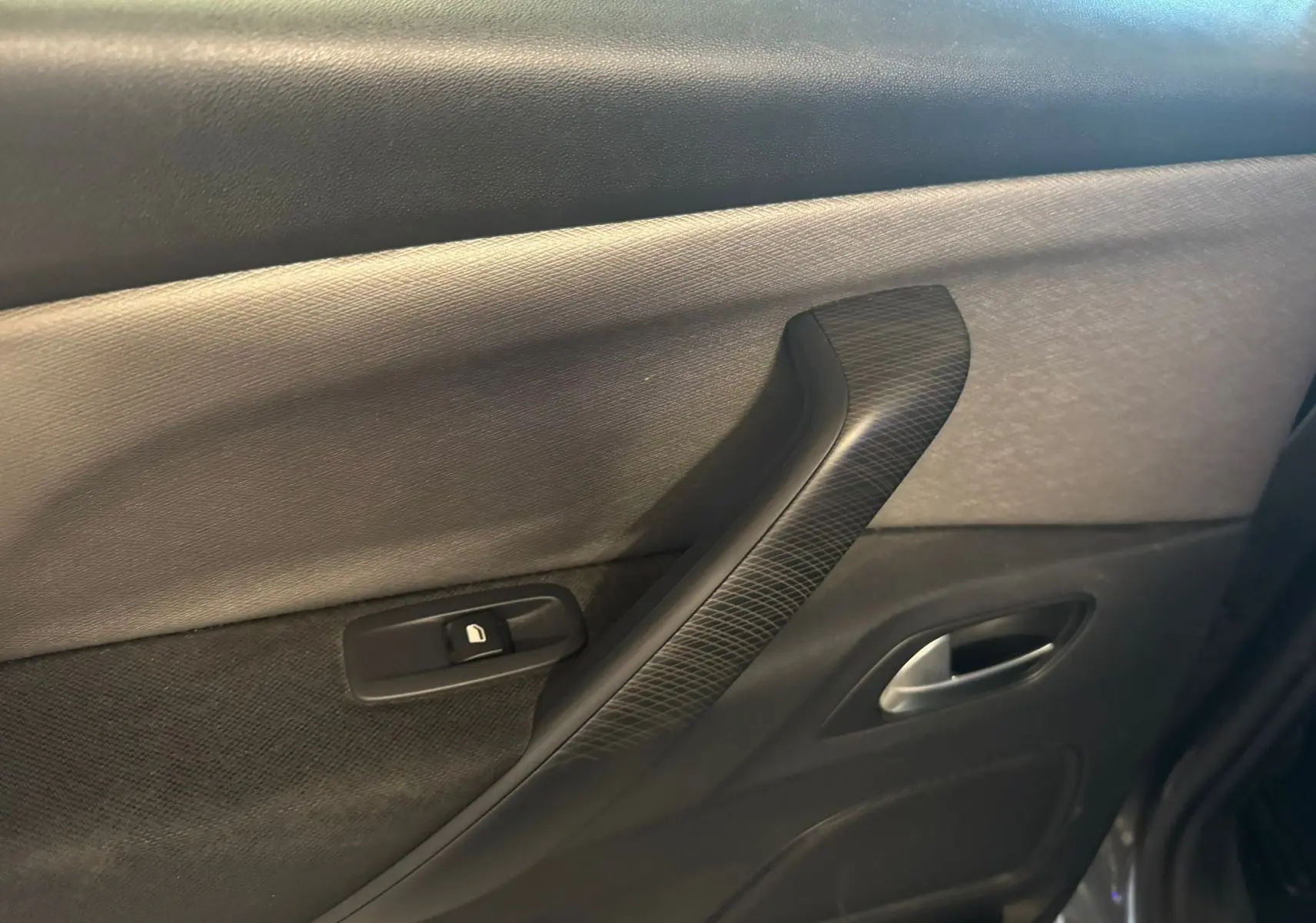 Gros plan sur la poignée intérieure côté droit de la porte arrière d'une Citroën C4 Picasso gris, avec bouton de verrouillage.