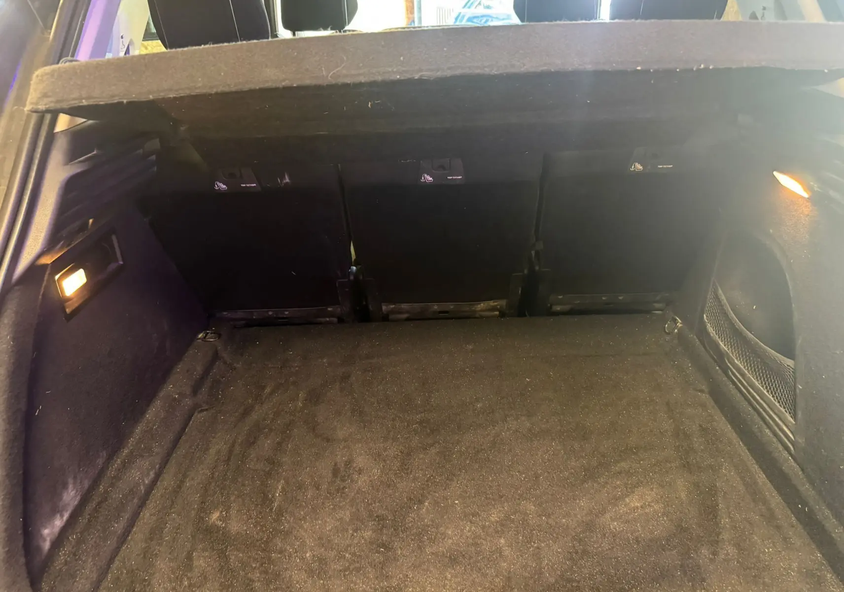 Coffre ouvert vu de l'arrière d'une Citroën C4 Picasso 2016, intérieur noir avec éclairage latéral.