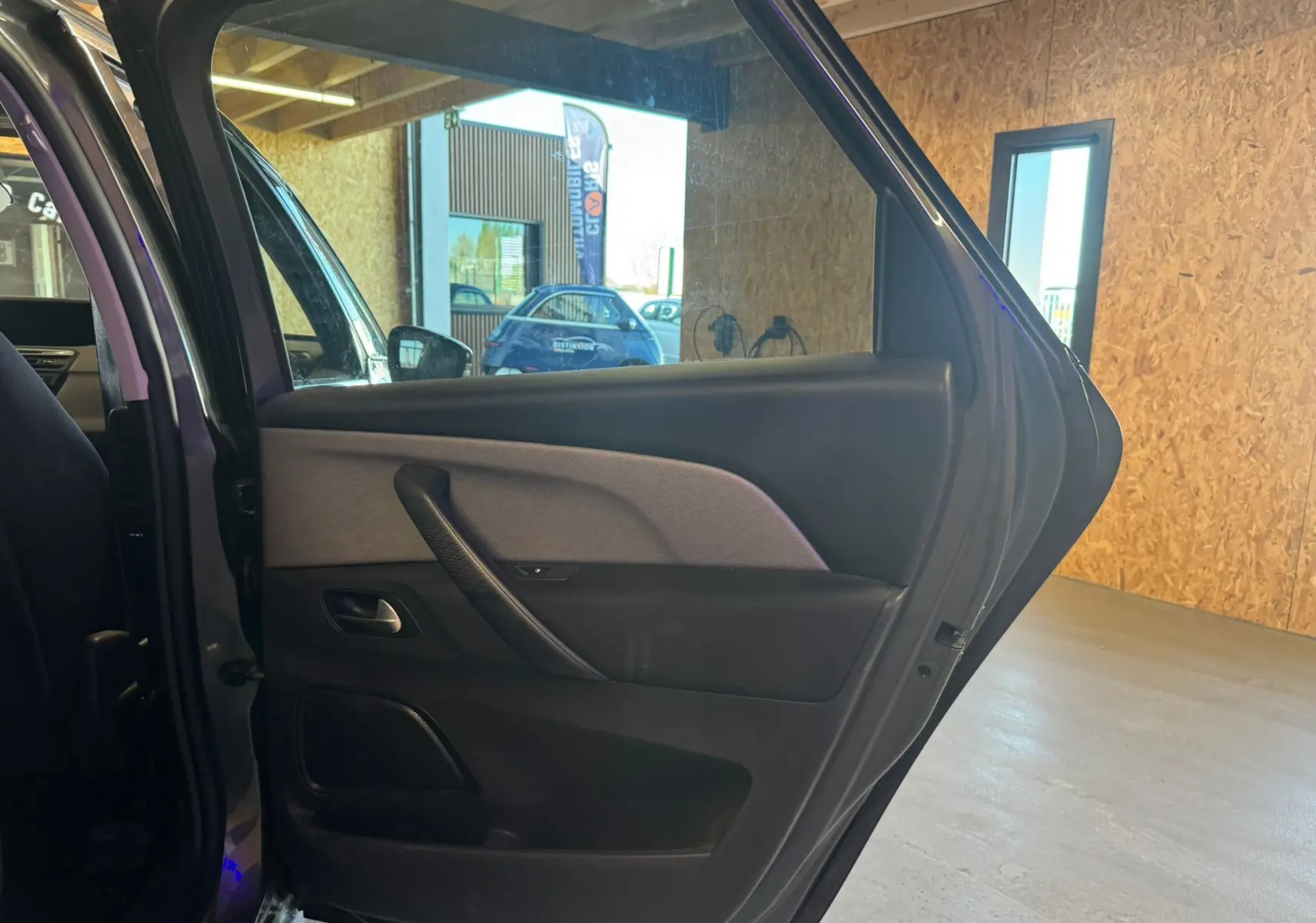 Vue intérieure côté gauche sur la porte arrière ouverte d'une Citroën C4 Picasso gris, montrant les finitions en tissu et plastique.